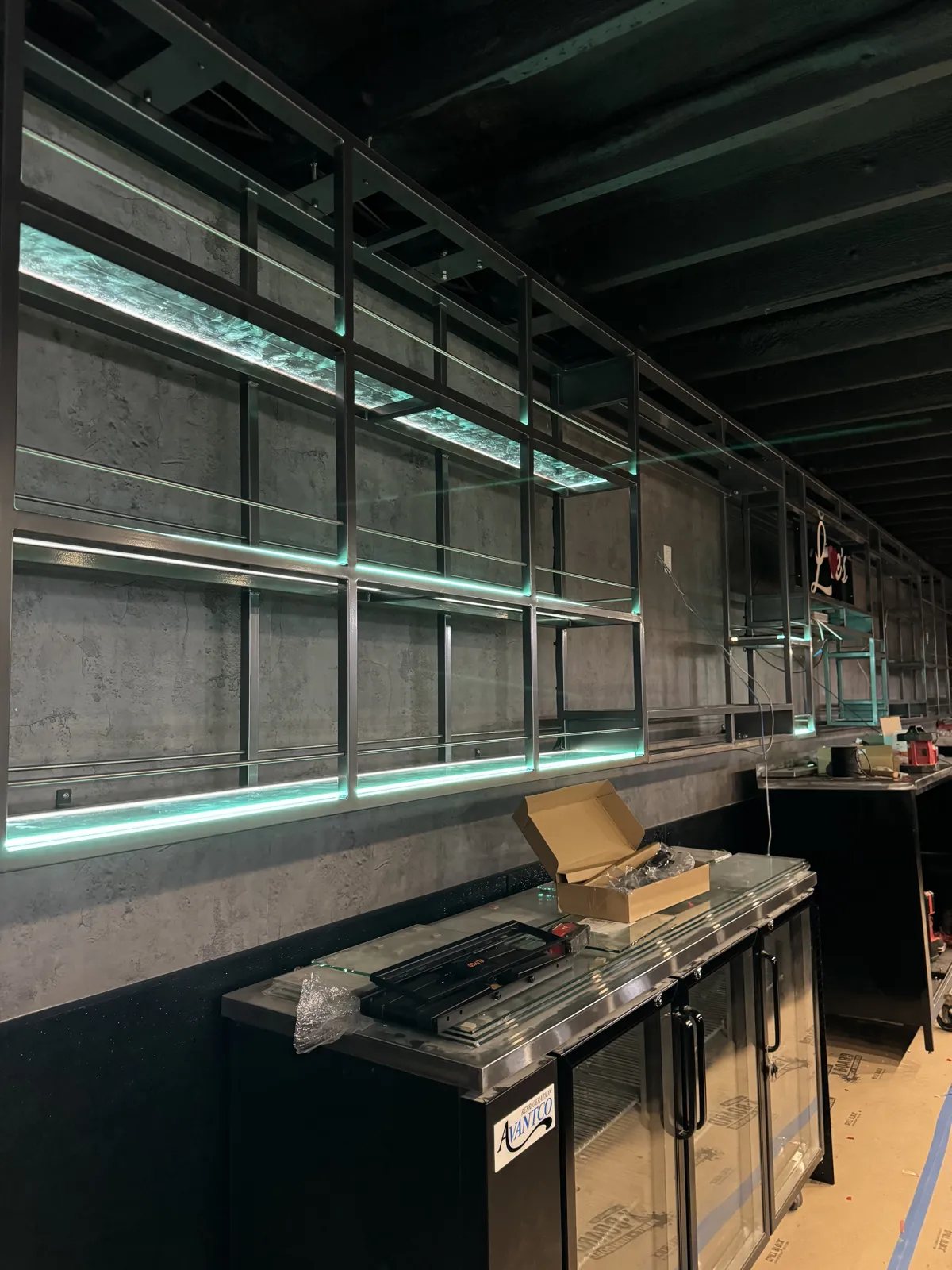 The same back-bar shelving lit up with LED strips