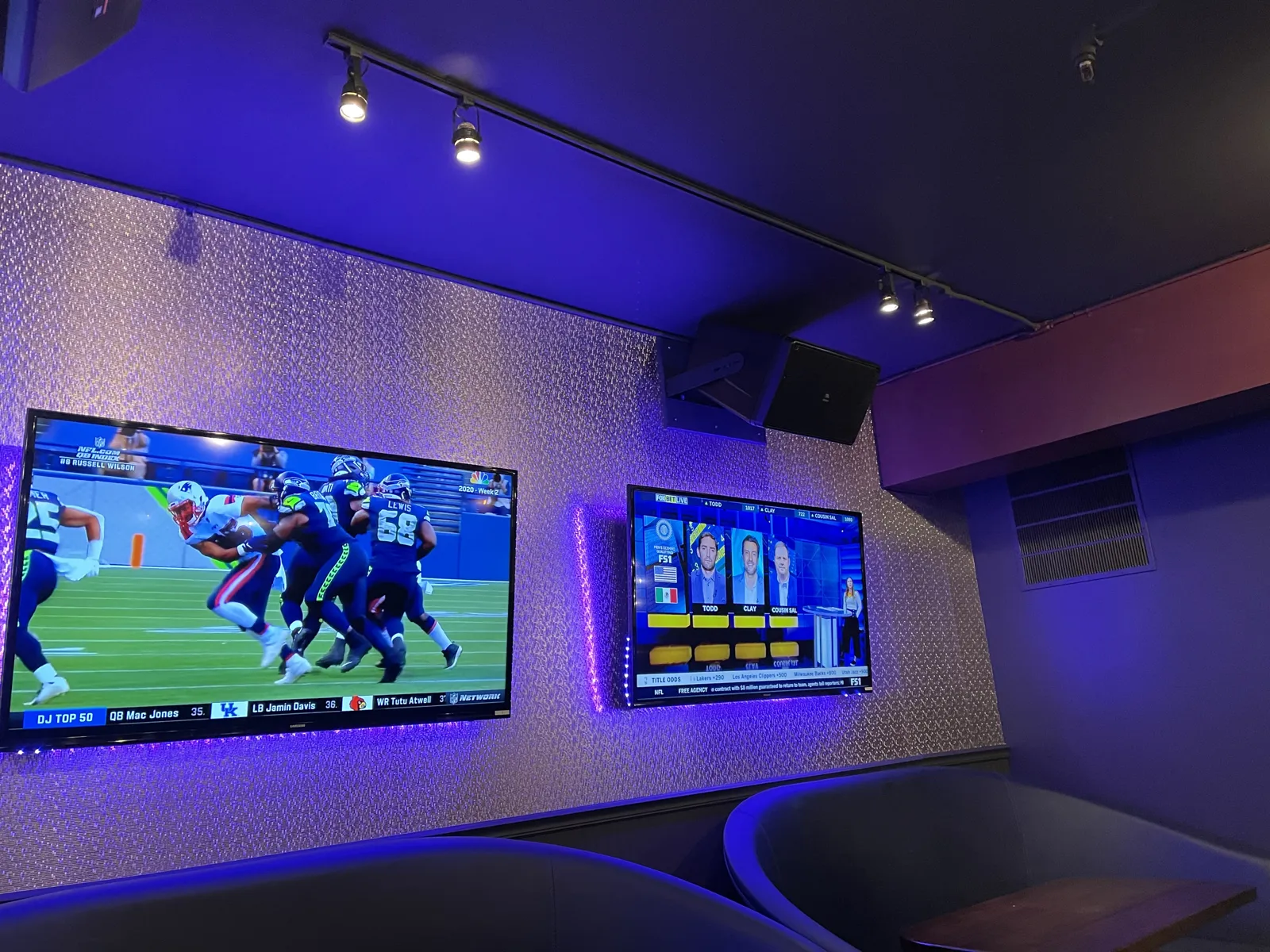 Bar seating area with mounted TVs and purple LED backlighting